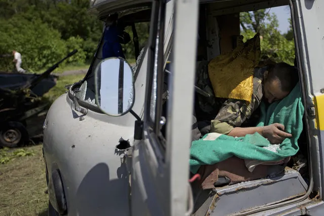 A body seen in a destroyed car near the village of Blahodatne, eastern Ukraine, on Thursday, May 22, 2014. At least 11 Ukrainian troops were killed and about 30 others were wounded when Pro-Russians attacked a military checkpoint, the deadliest raid in the weeks of fighting in eastern Ukraine. Three charred Ukrainian armored infantry vehicles, their turrets blown away by powerful explosions, and several burned vehicles stood at the site of the combat. (Photo by Ivan Sekretarev/AP Photo)