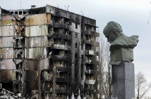 A monument to Taras Shevchenko, a Ukrainian poet and a national symbol, stands near an apartment ruined in the Russian shelling in the central square in Borodyanka, Ukraine, Wednesday, Apr. 6, 2022. (Photo by Efrem Lukatsky/AP Photo)
