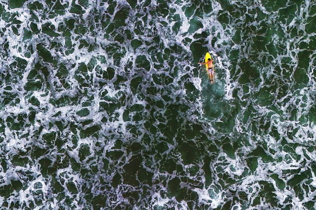 A surfer paddles out to the waves in the waters of Venao beach in Pedasi, Panama, Saturday, July 13, 2024. (Photo by Matias Delacroix/AP Photo)