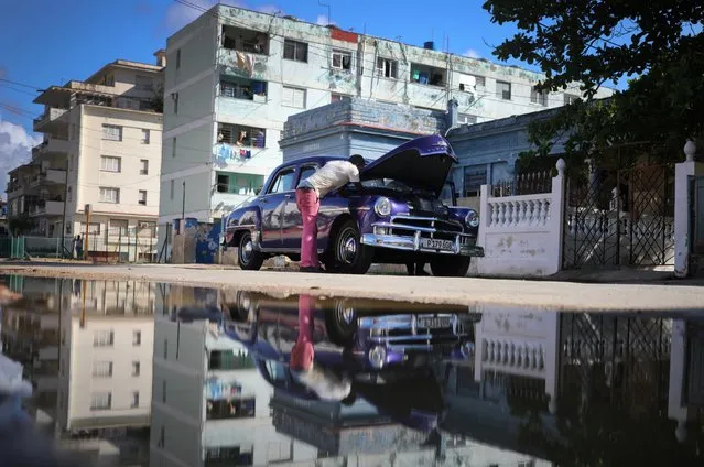 A man repairs a vintage American car on the side of the road in Havana, Cuba on March 26, 2019. (Photo by Phil Noble/Reuters)