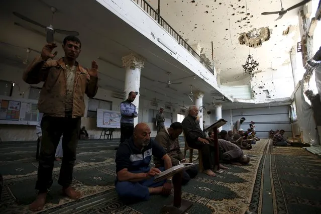 Palestinians pray and read the Koran inside a mosque that witnesses said was badly damaged by Israeli shelling during a 50-day war last summer, in the east of Gaza City May 6, 2015. (Photo by Mohammed Salem/Reuters)