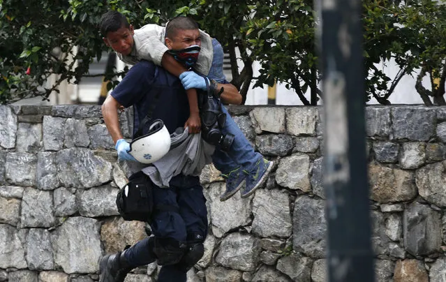 A medic carries a child to safety after he was affected by tear gas during protests in Caracas, Venezuela, Saturday, July 1, 2017. Demonstrators are taking the the streets after three months of continued protests that has seen the country's chief prosecutor Luisa Ortega barred from leaving the country and her bank accounts frozen, by the Supreme Court following her mounting criticisms of President Nicolas Maduro. (Photo by Ariana Cubillos/AP Photo)