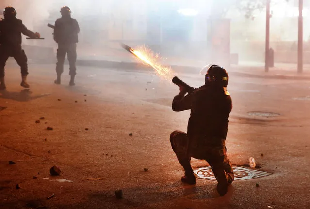 A riot policeman fires tear gas against the anti-government protesters, during ongoing protests against the Lebanese central bank's governor and against the deepening financial crisis, at Hamra trade street, in Beirut, Lebanon, Tuesday, January 14, 2020. Lebanese security forces lobbed tear gas at protesters who responded with rocks outside the country's central bank Tuesday, a violent turn after demonstrators returned to the streets following a weekslong lull. (Photo by Hussein Malla/AP Photo)