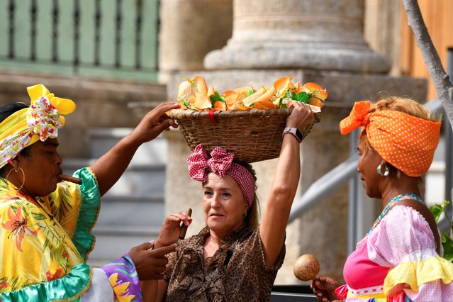 Cuban women in traditional costume prepare a tourist for a photo, after Cuba's power-grid operator said it had restored electricity to parts of the capital Havana on Monday, following a fourth major grid failure in 48 hours, in Havana, Cuba on October 21, 2024. (Photo by Norlys Perez/Reuters)