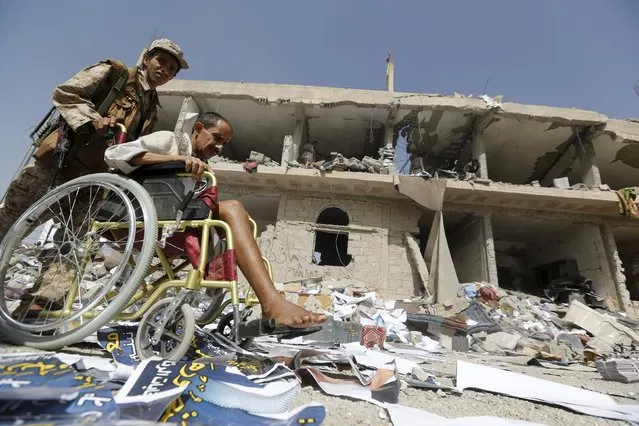A Houthi militant pushes the wheelchair of an injured comrade past the offices of the education ministry's workers union, destroyed by Saudi-led air strikes, in Yemen's northwestern city of Amran August 19, 2015. A Saudi-led Arab coalition has been bombarding the Iranian-allied Houthi rebel movement – Yemen's dominant force – since late March in a bid to reinstate exiled President Abd-Rabbu Mansour Hadi, who has fled to Riyadh. (Photo by Khaled Abdullah/Reuters)