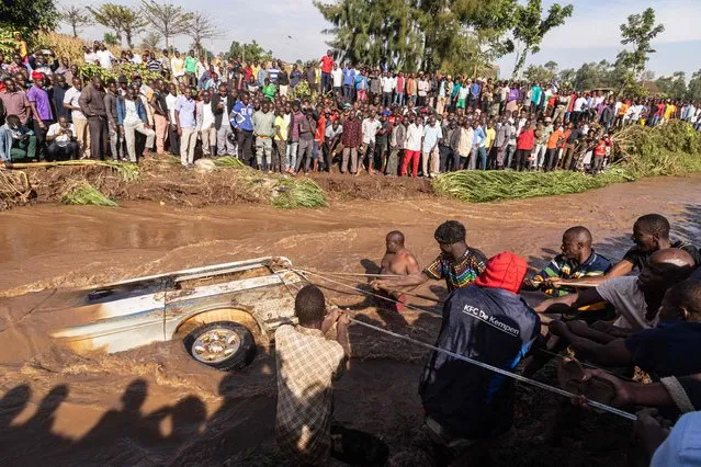 Villagers try to pull up the minibus in which 14 bodies were retrieved from inside in the river Nabuyonga in Namakwekwe, eastern Uganda, on August 1, 2022. The number of people killed in flash floods in the eastern Ugandan city of Mbale has jumped to 22, including a group of partygoers who became trapped in a minibus, police said on August 1, 2022. Two rivers burst their banks at the weekend after the city was battered by heavy rainfall, leading to mudslides that inflicted widespread damage and left many residents homeless. (Photo by Badru Katumba/AFP Photo)