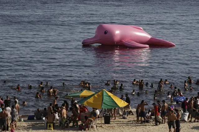An giant inflatable figure in the shape of a pink river dolphin floats offshore of the Ponta Negra beach along the Amazon river in Manaus, July 27, 2014. The figure was placed by organizers of the Red Alert conservation campaign which is trying to halt the killing of the dolphin which is illegal but common. (Photo by Bruno Kelly/Reuters)