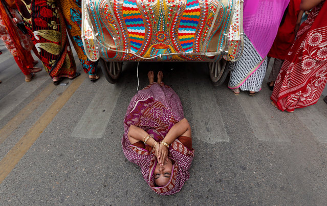 A Hindu devotee lies on a road as the holy “Rath”, or the chariot of lord Jagannath, passed over her during the Rath Yatra, or chariot procession in Karachi, Pakistan, July 17, 2016. Ratha-jatra is derived from two Odia words ratha/rotho meaning “chariot” and jatra meaning “journey”. The festival involves an annual procession (journey) of a deity's idols. Other names for the festival include ratha jatra or chariot festival. (Photo by Akhtar Soomro/Reuters)