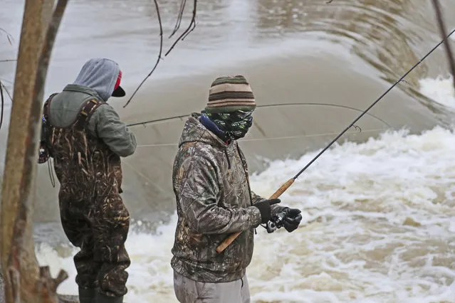 March 29, 2020 Fishing is still allowed under the stay at home order in Wisconsin. While the weather was windy and wet, and the water high, a group of fisherman on the Milwaukee River in Keltzsch Park in Glendale met a with some success fishing for steelhead or rainbow trout. Here fisherman on the bank fishing. Bandanas and balaclavas filled in for medical masks and kept the anglers warm as well. (Photo by Michael Sears/Milwaukee Journal-Sentinel via AP Photo)