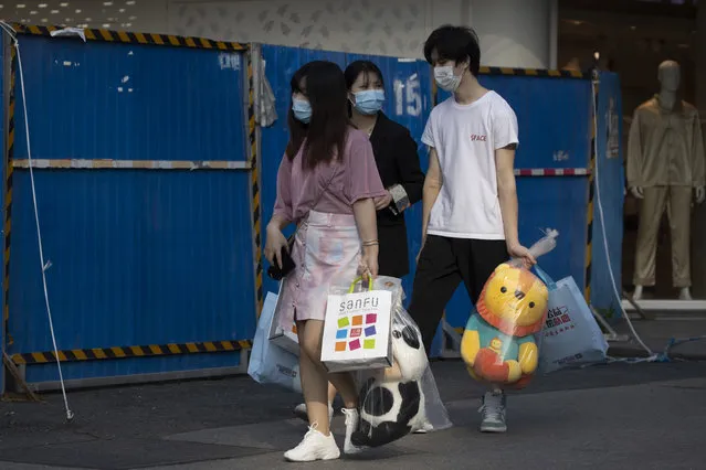 Residents carry their shopping at a retail street in Wuhan in central China's Hubei province on Thursday, April 9, 2020. Released from their apartments after a 2 1/2-month quarantine, residents of the city where the coronavirus pandemic began are cautiously returning to shopping and strolling in the street but say they still go out little and keep children home while they wait for schools to reopen. (Photo by Ng Han Guan/AP Photo)