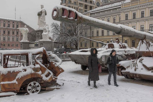 Pedestrians walks past destroyed Russian military vehicles blanketed in snow in front of Saint Michael's Golden-Domed Monastery, in downtown Kyiv, on November 22, 2023, amid the Russian invasion of Ukraine. (Photo by Roman Pilipey/AFP Photo)