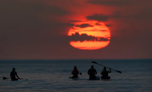 Paddleboarders and kayakers turn out to watch the sunrise at Cullercoats Bay, North Tyneside on Tuesday, July 19, 2022. Britons are set to melt on the hottest UK day on record as temperatures are predicted to hit 40C. (Photo by Owen Humphreys/PA Images via Getty Images)