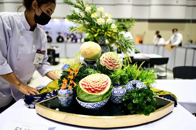 A participant arranges her carved fruits and vegetables decoration during a fruit and vegetable carving competition at the 26th Thailand International Culinary Cup in Bangkok on September 21, 2022. (Photo by Manan Vatsyayana/AFP Photo)