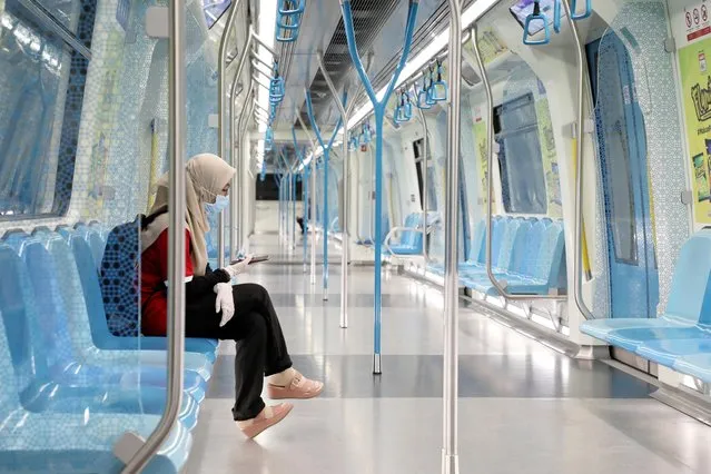 A woman wearing protective mask and gloves, uses her phone in a Mass Rapid Transit train, during the movement control order due to the outbreak of the coronavirus disease (COVID-19), in Kuala Lumpur, Malaysia on March 22, 2020. (Photo by Lim Huey Teng/Reuters)