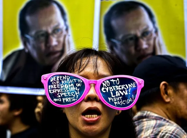 A protester stands in front of picture of Philippine President Benigno Aquino III, during a rally against the anti-cybercrime law in front of the Supreme Court in Manila, on October 9, 2012. The Philippine Supreme Court suspended implementation of the country's anti-cybercrime law while it decides whether certain provisions violate civil liberties. (Photo by Aaron Favila/Associated Press)