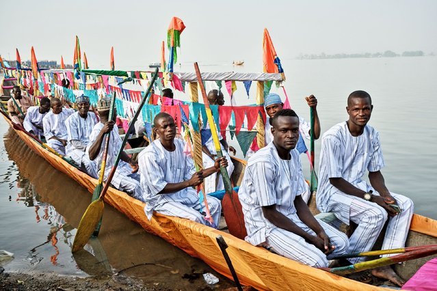 Men sit in their pirogue as they prepare for the annual boat regatta in Yauri, Kebbi State, Nigeria on February 15, 2025. The regatta festival started about 200 years ago as a display of naval strength of the Gungu people, where the Gungu warriors annually attacked dangerous hippopotamus that were destroying farmlands. Warriors would board various sizes of canoes with different types of weapons to attack the animal on the River Niger. This required expertise in canoe paddling and naval warfare. It also served as training exercise for upcoming Gungu warriors. (Photo by Toyin Adedokun/AFP Photo)