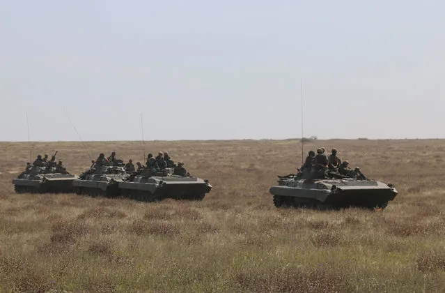 Ukrainian servicemen ride atop armored personnel carriers (APC) during a military drill in Kherson region, Ukraine, August 12, 2016. (Photo by Reuters/Stringer)