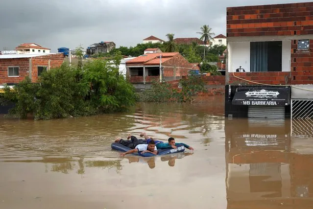 Men use an inflatable mattress to navigate during a flood caused by heavy rains, in Itapetinga, Bahia State, Brazil, on December 26, 2021. The death toll from heavy rains that have battered the Brazilian state of Bahia since November rose to 18 on Sunday, amid incessant torrents that have displaced 35,000 people, authorities said. Two people are also missing, while 19,580 have been displaced and another 16,001 forced to seek shelter, bringing the number of people driven from their homes to 35,000, the Bahia civil protection agency Sudec said. (Photo by Manuella Luana/AFP Photo)