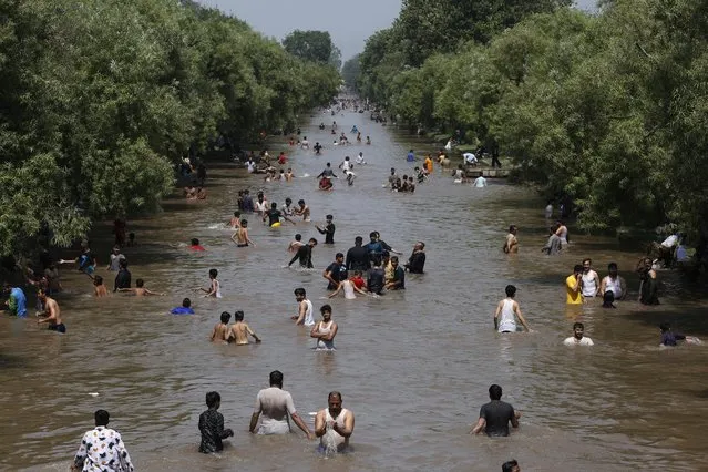 People take bath into a canal as the weather turns warm in Lahore, Pakistan, Tuesday, May 26, 2020. (Photo by K.M. Chaudhary/AP Photo)
