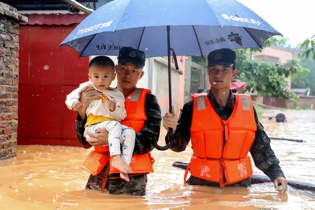 This photo taken on June 8, 2020 shows rescuers evacuating a child in a flooded area after heavy rain in Qingyuan in China's southern Guangdong province. (Photo by AFP Photo/China Stringer Network)