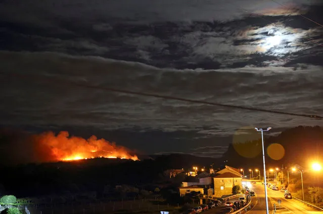 A photo made available 19 August 2016 of a forest fire near several homes in the A Portela hills near the village of Curro, Galicia, northeastern Spain, late 18 August 2016. After weeks of wild fires the situation in the Galician mountains start to ease, although a few fires are still active in the region. (Photo by EPA/Sxenick)