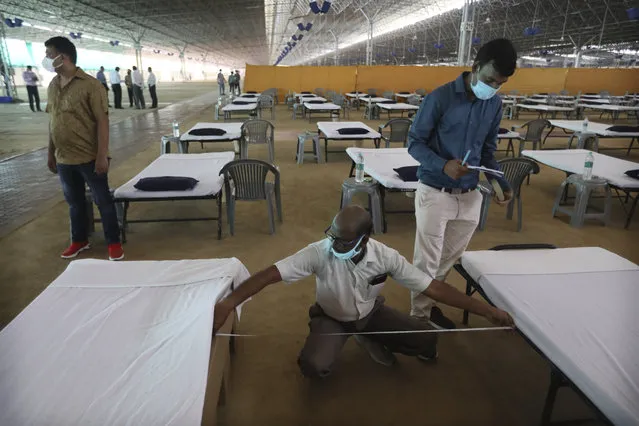 Volunteers measure the space between beds as they prepare a facility that can accommodate more than ten thousand COVID-19 patients at the Radha Soami Satsang Beas complex, one of the biggest in India, in the Chattarpur area of New Delhi, India, Wednesday, June 24, 2020. New Delhi, which is among India's worst hit three states is emerging a cause of concern for the federal government and is being criticized for its poor contact tracing and a lack of enough hospital beds as India is the fourth hardest-hit country by the pandemic in the world after the U.S., Russia and Brazil. (Photo by Manish Swarup/AP Photo)