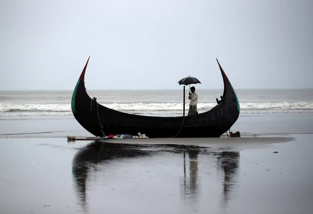 A man holds an umbrella as he stands on a boat, which capsized with a group of Rohingya refugees at Bailakhali, near Cox's Bazar, Bangladesh, October 31, 2017. (Photo by Hannah McKay/Reuters)