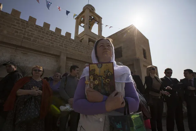 A Christian pilgrim holds a cross before a ceremony at the baptismal site known as Qasr el-Yahud on the banks of the Jordan River near the West Bank city of Jericho January 18, 2014. (Photo by Baz Ratner/Reuters)