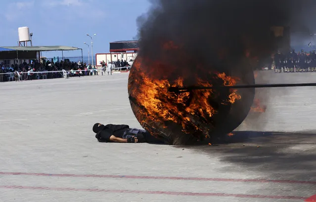 A Palestinian member of Hamas security force lies under a fired wood wheel, while displaying his military skills during a police academy graduation ceremony in Gaza City, Tuesday, September 6, 2016. (Photo by Adel Hana/AP Photo)