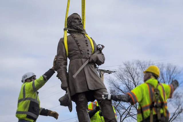 Workers begin to lay the bronze statue of Confederate General A.P. Hill onto a flatbed truck on Monday December 12, 2022 in Richmond, Va. The city of Richmond – the capital of the Confederacy for most of the Civil War – removed the statue,  its last city-owned Confederate statue Monday, more than two years after it began to purge itself of what many saw as painful symbols of racial oppression. (Photo by John C. Clark/AP Photo)