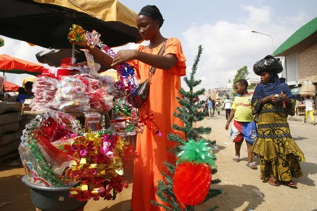 A female vendor sells Christmas and New Year paraphernalia from her stall at a roadside in Abidjan, Ivory Coast, 16 December 2022. A few days before the Christmas holidays and with the celebrations of New Year's Eve and New Year's Day in sight, the shopping for seasonal decoration in the West African city is at its peak. (Photo by Legnan Koula/EPA/EFE)