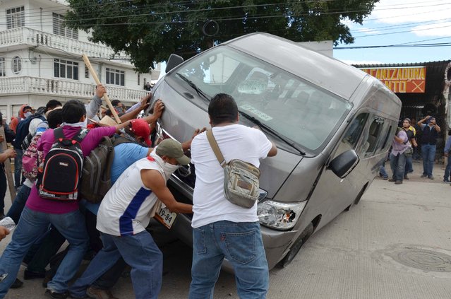 Teachers flip a vehicle during a clash with riot police in Chilpancingo, Mexico, Tuesday, November 11, 2014. (Photo by Alejandrino Gonzalez/AP Photo)