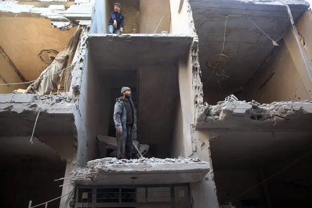 Syrians inspect the damage in a residential building hit in air strikes by regime forces on Arbin, in the rebel-held Eastern Ghouta region on the outskirts of the Syrian capital Damascus, on February 1, 2018. Arbin is in the Eastern Ghouta region which has been under government siege since 2013. (Photo by Amer Almohibany/AFP Photo)