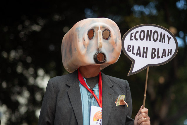 A man wearing a home-made mask takes part in a protest, organised by Extinction Rebellion against the South African government's ongoing commitment to use fossil fuels, outside the the venue for the Africa Energy Indaba in Cape Town on March 5, 2024. (Photo by Rodger Bosch/AFP Photo)