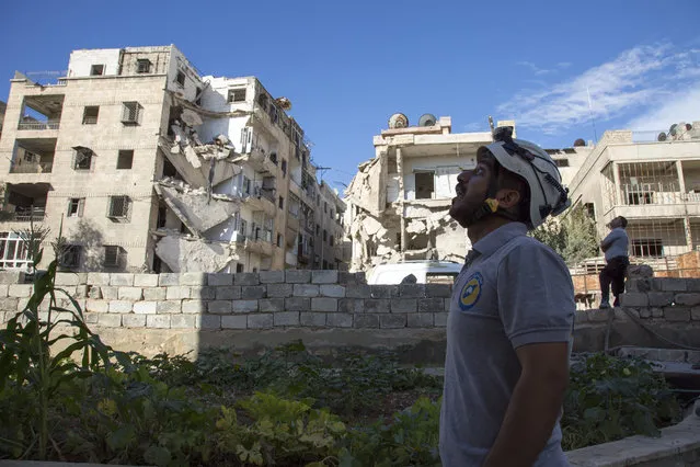 A Syrian rescuer looks towards the sky following an air strike in the rebel-held Ansari district in the northern Syrian city of Aleppo on September 23, 2016. Syrian and Russian aircraft pounded rebel-held areas of Aleppo, a monitor said, after the army announced a new offensive aimed at retaking all of the divided second city. An AFP correspondent in the opposition-held east of the city reported relentless bombardment with air strikes, barrel bombs and artillery fire hitting multiple neighbourhoods. (Photo by Karam Al-Masri/AFP Photo)