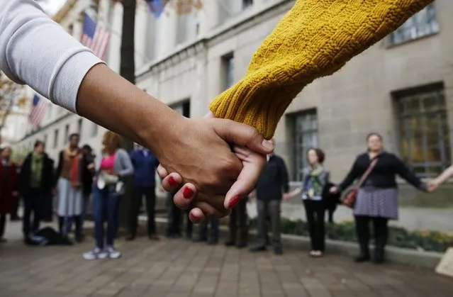 Protestors hold hands as they rally against the Ferguson,Mo. Grand Jury exoneration of police officer Darren Wilson for his August 2014 shooting and killing of Michael Brown while at the U.S. Justice Department in Washington, December 1, 2014. U.S. President Obama asked Congress on Monday for $263 million for the federal response to the civil rights upheaval in Ferguson, Missouri, and is setting up a task force to study how to improve modern-day policing. (Photo by Larry Downing/Reuters)