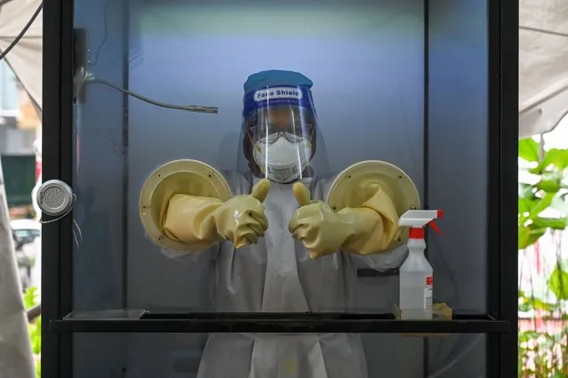 A health worker gives a thumbs-up as she stands in a non-contact chamber called the “CoV SHIELD” before taking swabs to test for the COVID-19 novel coronavirus at Sunway Medical Center in Subang Jaya, on the outskirts of Kuala Lumpur, on October 22, 2020. (Photo by Mohd Rasfan/AFP Photo)