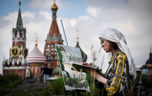 A girl paints in front of the Kremlin's Spasskaya tower and St. Basil's cathedral in downtown Moscow on July 23, 2025. Russian and Ukrainian officials are due to meet in Istanbul on Wednesday for a third round of peace talks, their first meeting in more than seven weeks amid US pressure to reach a ceasefire. (Photo by Alexander Nemenov/AFP Photo)
