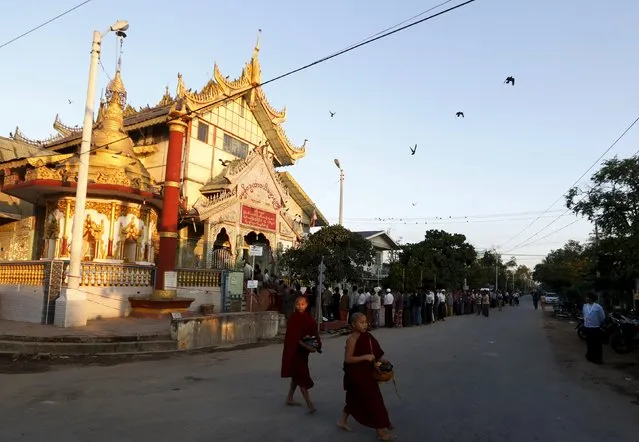 Monks walk past a Buddhist prayer hall as people queue to vote during the general election in Mandalay, Myanmar, November 8, 2015. (Photo by Olivia Harris/Reuters)