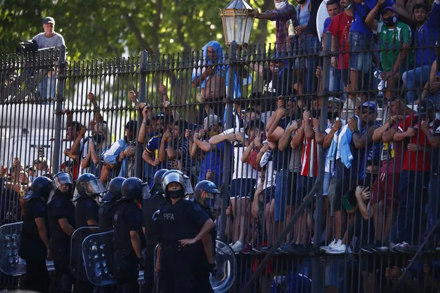 Mourning fans climb the fence of the presidential palace to get a glimpse of the casket carrying Diego Maradona's body in Buenos Aires, Argentina, Thursday, November 26, 2020. (Photo by Marcos Brindicci/AP Photo)