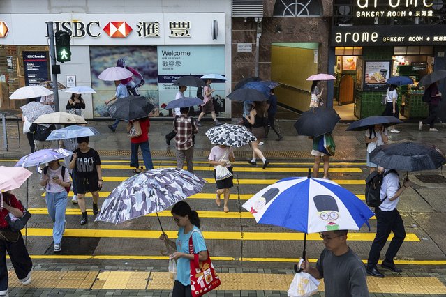 People hold umbrellas in the rain in Hong Kong, Thursday, August 14, 2025 as Tropical Storm Podul was moving away from the partially autonomous city. (Phoot by Chan Long Hei/AP Photo)