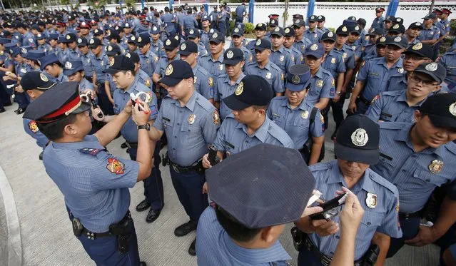 Police officers seal the muzzles of firearms of policemen during a sealing of firearms ceremony at the National Capital Region Police Office in Taguig, Metro Manila, December 22, 2014. (Photo by Erik De Castro/Reuters)