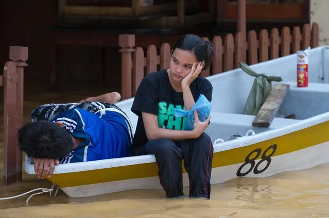 A woman (C) looks on as she waits inside a boat as her house submerged in floodwaters in Pengkalan Chepa, near Kota Bharu on December 27, 2014. Rescue teams struggled on December 27 to reach inundated areas of northeast Malaysia as victims accused the government of being slow to provide assistance after the country's worst flooding in decades. (Photo by Mohd Rasfan/AFP Photo)