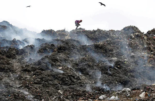 A man collects recyclable materials as smoke billows from a burning garbage dump site on the occasion of Earth Day, in Kolkata, India, April 22, 2018. (Photo by Rupak De Chowdhuri/Reuters)