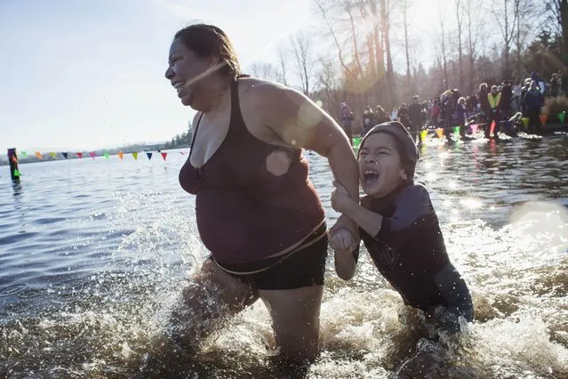 A woman drags her son into Lake Washington during the 13th annual Polar Bear Plunge at Matthews Beach Park in Seattle, Washington January 1, 2015. (Photo by David Ryder/Reuters)
