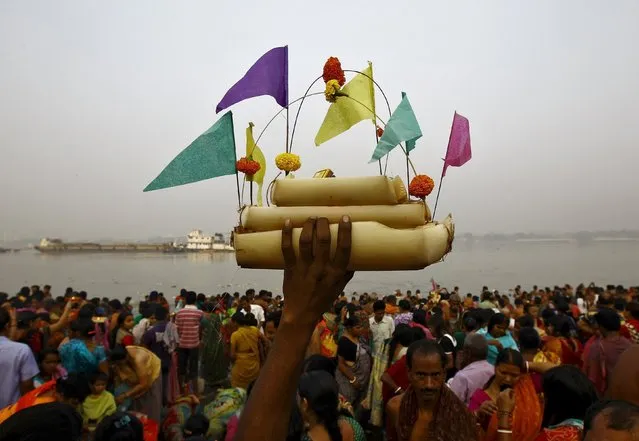 A Hindu man holds up a small decorated boat made with banana stem as people gather to take a holy dip in river Ganges on the occasion of Guru Purnima in Kolkata, India, November 25, 2015. Guru Purnima is observed to pay respects to one's "guru" or teacher who symbolises the Hindu Trinity of Brahma, Vishnu and Maheshwar, believed to be the creators of the universe. (Photo by Rupak De Chowdhuri/Reuters)