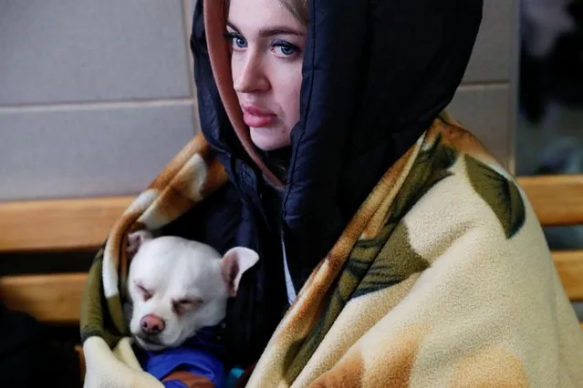 A woman fleeing Russia's invasion of Ukraine rests at the train station with her dog in Zahony, Hungary on March 4, 2022. (Photo by Bernadett Szabo/Reuters)
