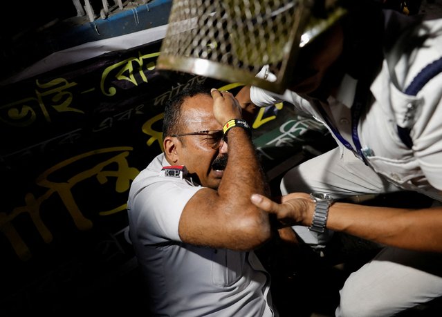 An injured Kolkata police official is moved to safety after Hindu activists try to break a police barricade as they participate in a protest demanding the release of the Bangladeshi jailed Hindu monk leader Chinmoy Krishna Das Brahmachari, in Kolkata, India on November 28, 2024. (Photo by Sahiba Chawdhary/Reuters)