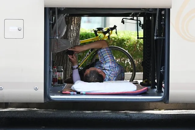 A bus driver shelters from the sun in the luggage compartment of his bus during a heatwave in Beijing on June 23, 2023. (Photo by Greg Baker/AFP Photo)