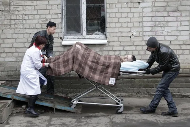 An injured soldier is pushed on a stretcher outside of a hospital in the town of Artemivsk, Ukraine, Friday, January 30, 2015. (Photo by Petr David Josek/AP Photo)